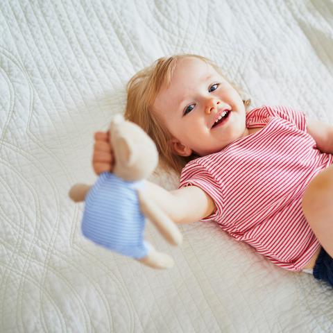 Krippenkind mit Teddybär im Schlafraum