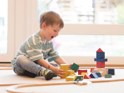 Kindergartenkind spielt mit Holzbausteinen