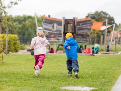 Kinder rennen zusammen im Garten der Kita