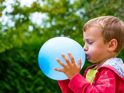 Kindergartenkind macht Atemübung mit Luftballon