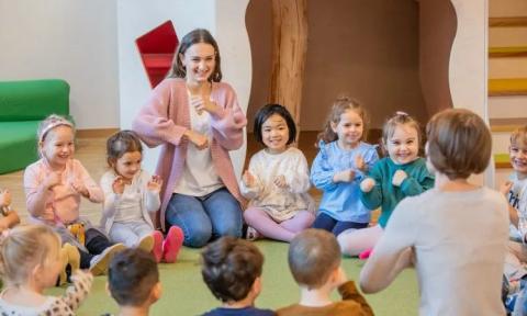 Kinder und Erzieherin im Kreis sitzend